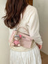 Pink faux leather crossbody bag worn over the shoulder, showing the back panel and bear charm
