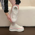 White platform sneaker held to show the laces, collar and insole