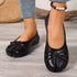 Front view of black bow flats with jeans and ankle jewelry