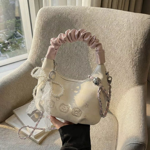 Cream ruched-handle purse resting on a cushion
