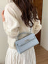 Blue croc-embossed bag worn over the shoulder, showing the back panel and top handle