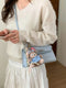 Blue croc-embossed faux leather crossbody bag worn at the hip with a teddy bear charm