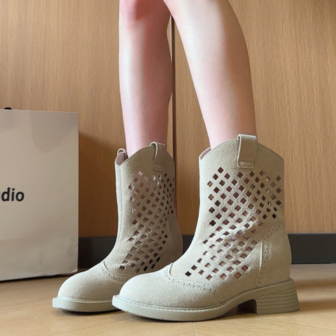 Beige perforated ankle boots worn with bare legs, showing low block heels