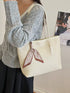 Side view of beige woven shoulder tote carried on a model's shoulder