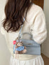 Blue faux leather crossbody bag shown from the side on a model with a cream sweater