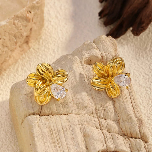 Close-up of gold-plated floral studs on textured stone