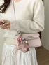 Pink croc-embossed crossbody bag worn at the hip with a pink teddy bear charm