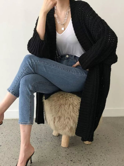 Black chunky longline cardigan worn open with jeans, seated view