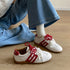 White-and-red retro sneakers worn beside wide-leg denim