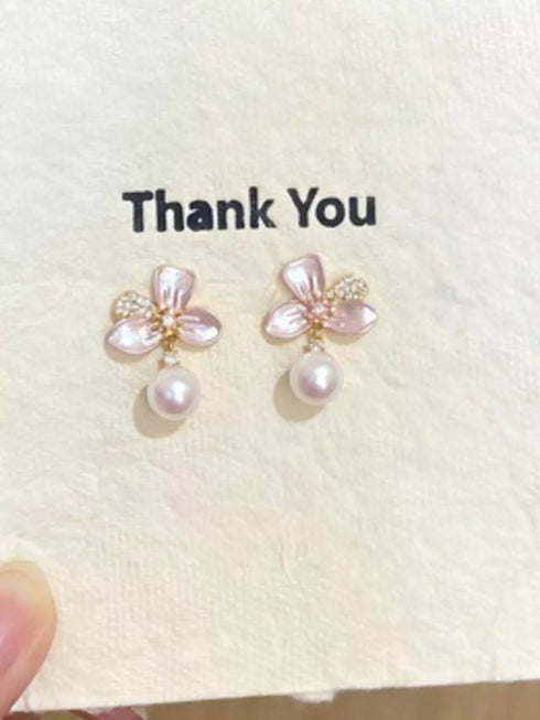 Close-up of flower earrings and dangling synthetic pearls on a card