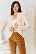 Cream textured cardigan worn open with hands at the front edges