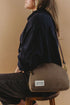Hopper crossbody worn over a dark shirt while seated