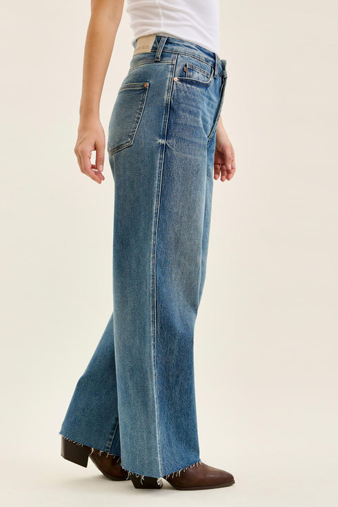 Judy Blue Wilhelmina jeans at an angle showing the raw hem above brown boots