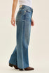 Judy Blue Wilhelmina jeans at an angle showing the raw hem above brown boots