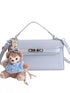 Blue croc-embossed faux leather bag with top handle, crossbody strap and teddy bear charm on white