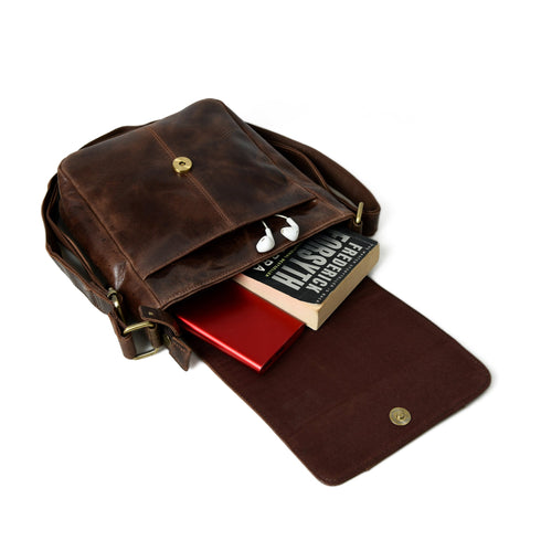Brown crossbody bag open with book and small items shown as props