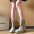 Front view of beige western ankle boots with square cutouts and pull tabs