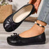 Black bow flats showing one worn shoe and one held above