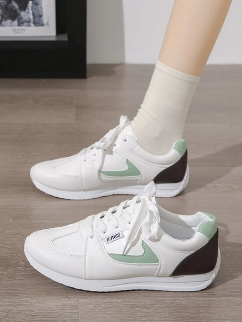 Side view of green-accent white sneakers with dark heel panels