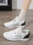 Side view of green-accent white sneakers with dark heel panels