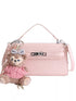 Pink croc-embossed faux leather bag with top handle, strap and teddy bear charm on white