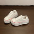Pair of white platform sneakers at an angle showing red piping around the sole