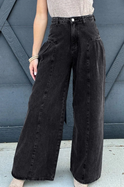 Black high-rise wide-leg jeans worn from the front with hands in the pockets