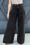 Black high-rise wide-leg jeans worn from the front with hands in the pockets