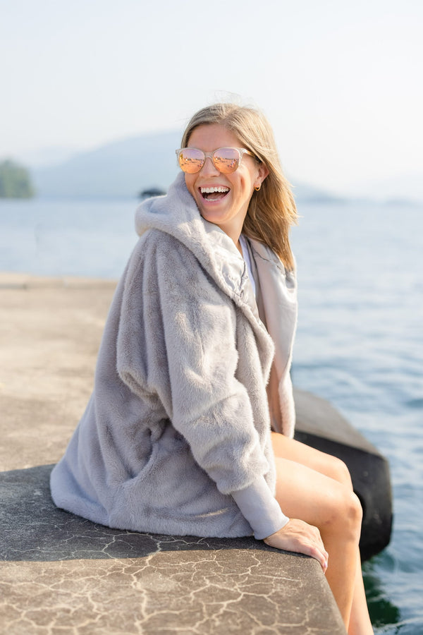 Pretty Rugged Grey faux fur hooded cardigan worn open by a lakeside seating area