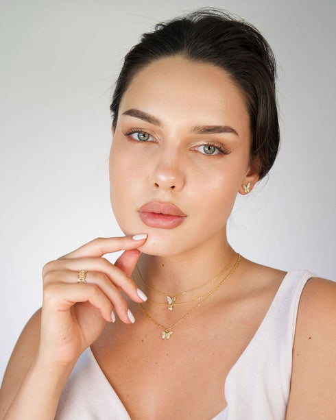 Model wearing butterfly studs with hand near chin