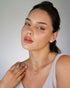 Model wearing small butterfly studs with a pale pink top