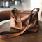 Brown RockCow leather crossbody with adjustable strap on a chair