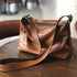 Brown RockCow leather crossbody with adjustable strap on a chair