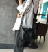 Black leather crossbody worn with a white shirt and dark trousers