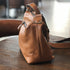 Side view of brown leather bag showing strap attachment