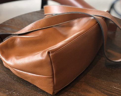 Bottom view of brown leather crossbody showing the curved base