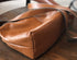 Bottom view of brown leather crossbody showing the curved base