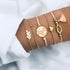 Rose-tone bracelet stack with pale peach tassel and globe detail