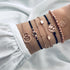 Rose-tone bracelet stack with navy cord, geometric and globe motifs