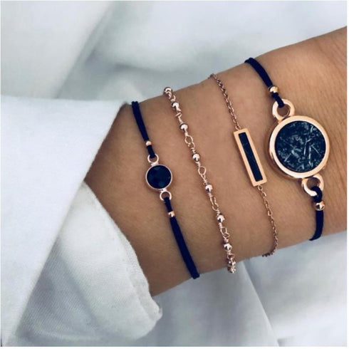 Navy cord and rose-tone charm bracelets worn together on a wrist
