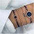 Navy cord and rose-tone charm bracelets worn together on a wrist