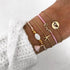 Pink and gold-tone bracelet stack with love, starfish-shaped and globe details