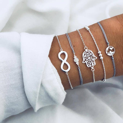 Silver-tone bracelet stack with infinity, hand-shaped and globe charms