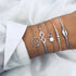 Silver-tone bracelet stack with spiral, infinity and shell-shaped charms