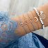 Gold-tone and pale bead bracelet stack with heart, crescent and openwork charm