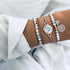 Gray bead and rose-tone bracelets with pale round centerpiece and heart charm