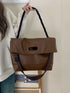 Brown shoulder bag held by braided strap with long strap hanging below
