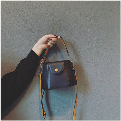 Black mini bucket bag held by its short handle