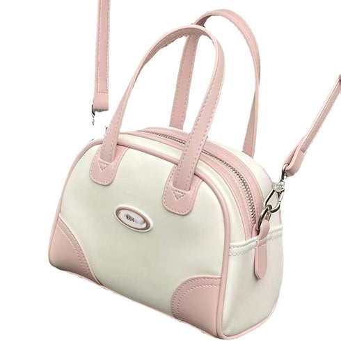 Pink-and-white mini bowling bag with long crossbody strap on white