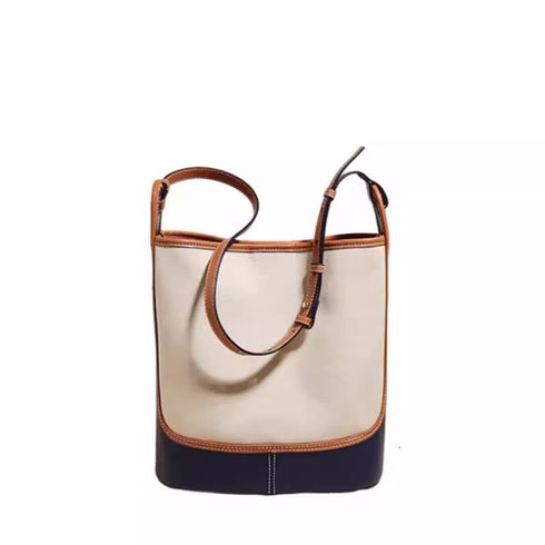 Front view of beige and navy bucket-style shoulder bag with buckle strap